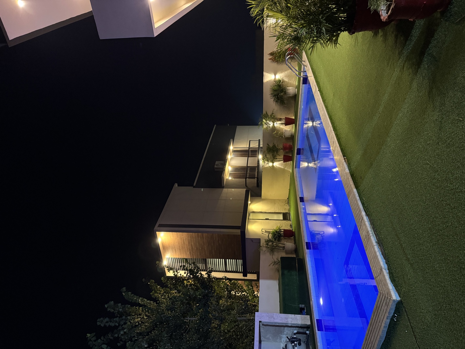 Farmhouse pool and lawn lit up at night