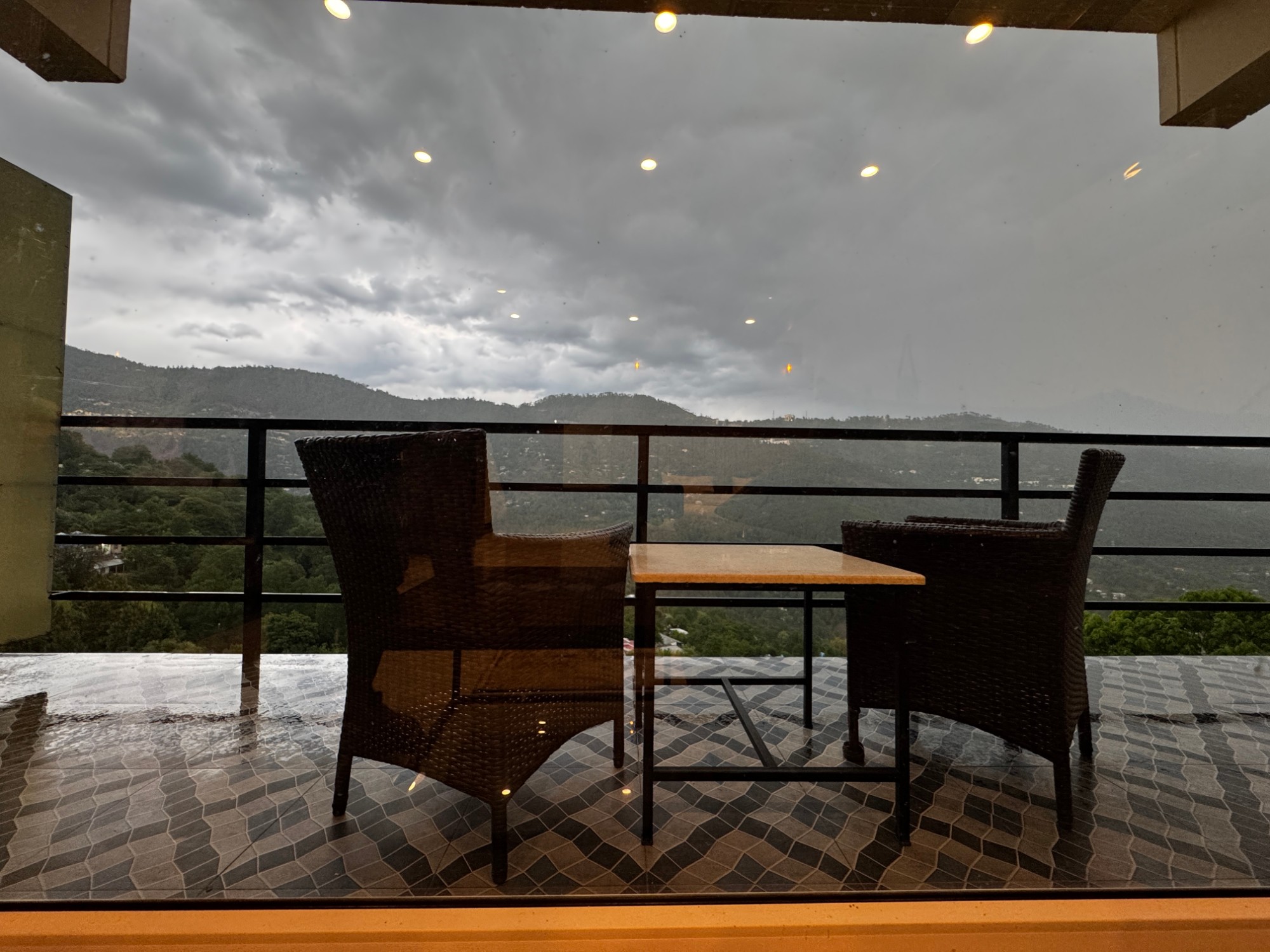 Private balcony with wicker chairs and a view of the Murree hills under monsoon clouds