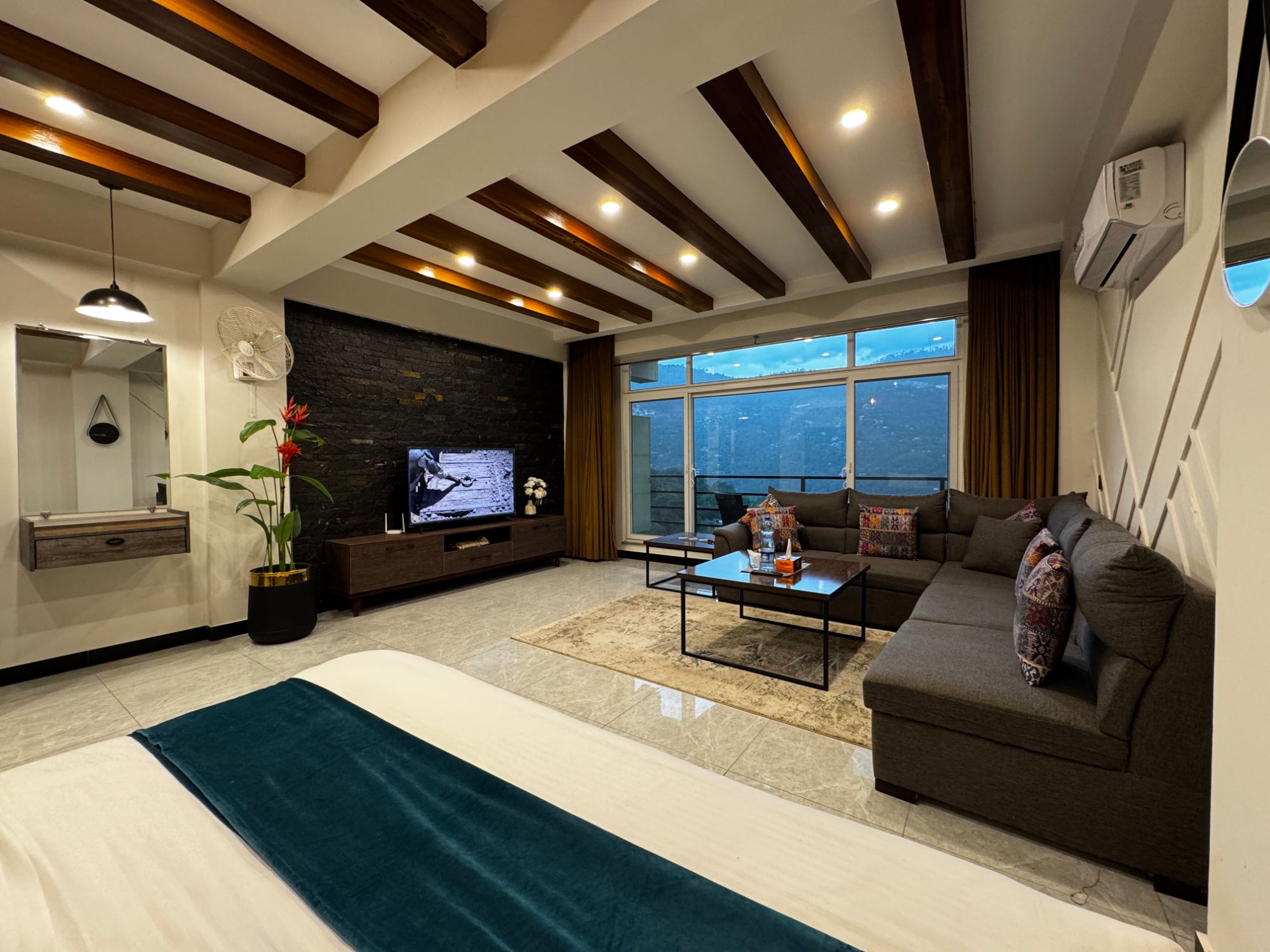 Murree Spring Apartments Studio: open-plan living space with wood-beam ceiling and valley-view windows