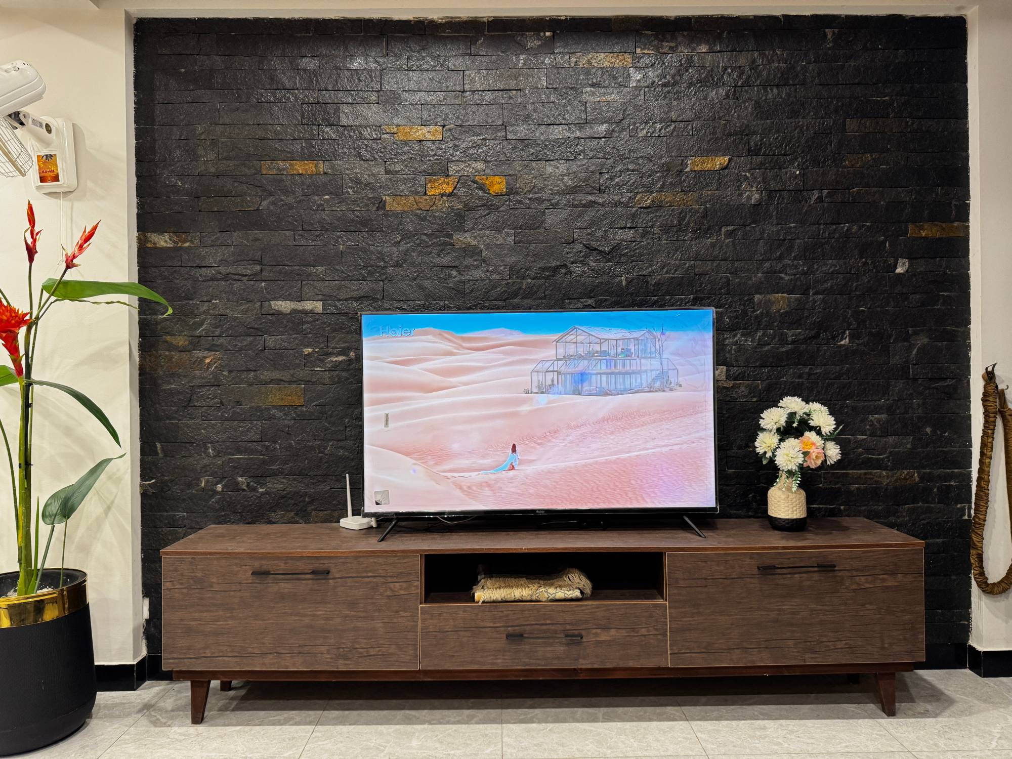 Black stone feature wall with smart TV on a walnut media console