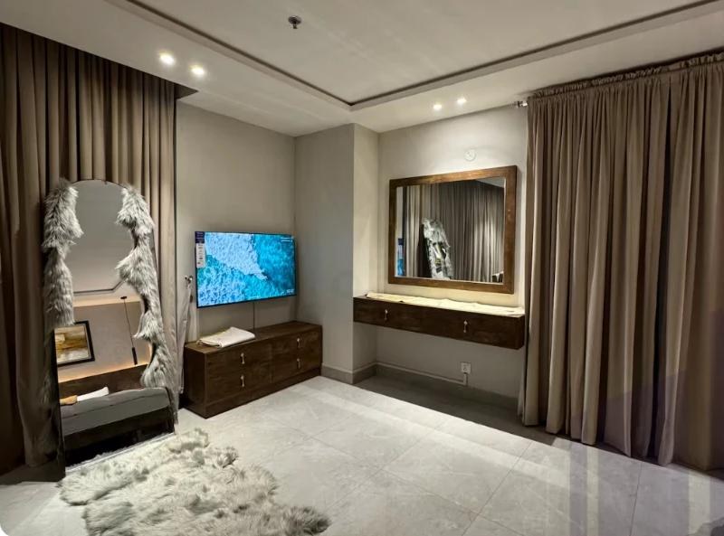 Bright condo in Rawalpindi with floor mirror, wall TV and neutral curtains